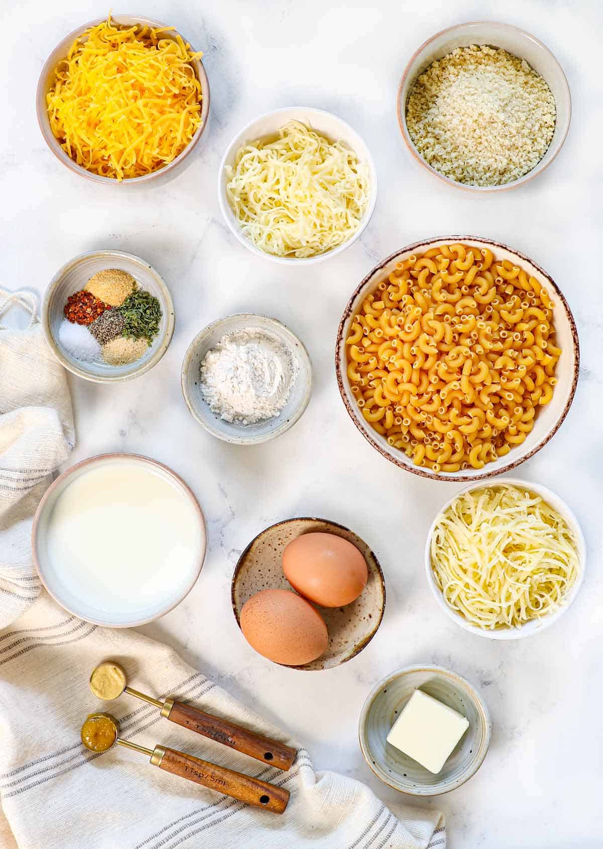 top view of mac and cheese bites ingredients: macaroni, cheddar, fontina, gruyere, flour, eggs, milk, spices butter, panko, dijon mustard