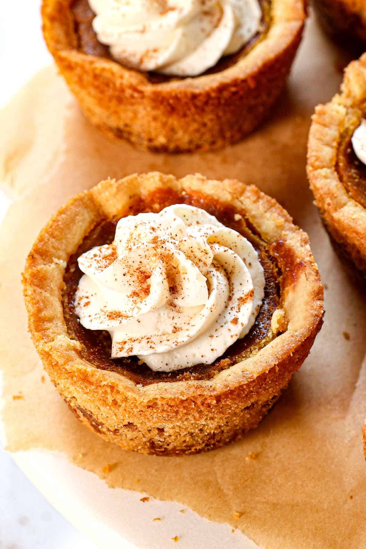 up close of a mini pumpkin pie topped with whipped cream and ground cinnamon