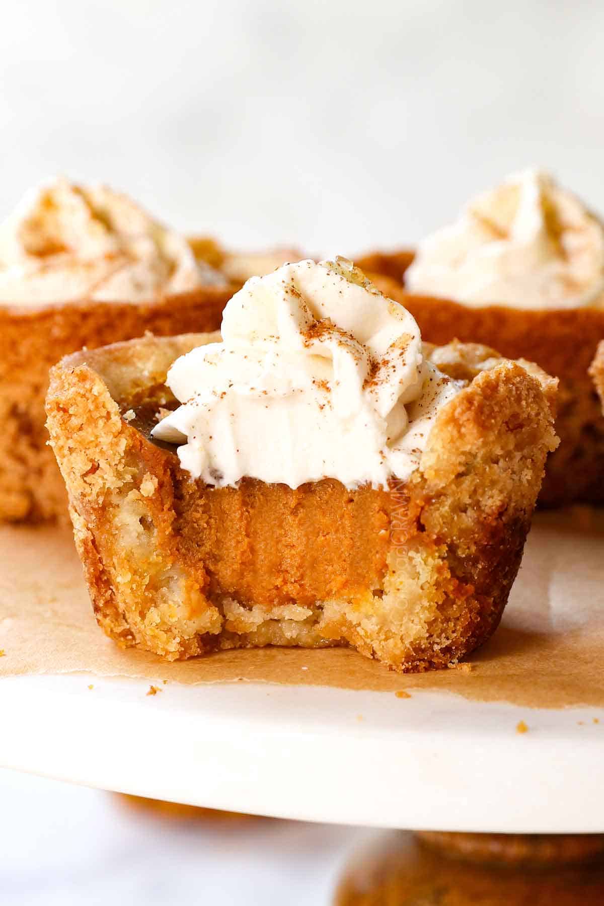up close of a mini pumpkin pie with a bite taken out of it showing the creamy, silking pumpkin pie filling