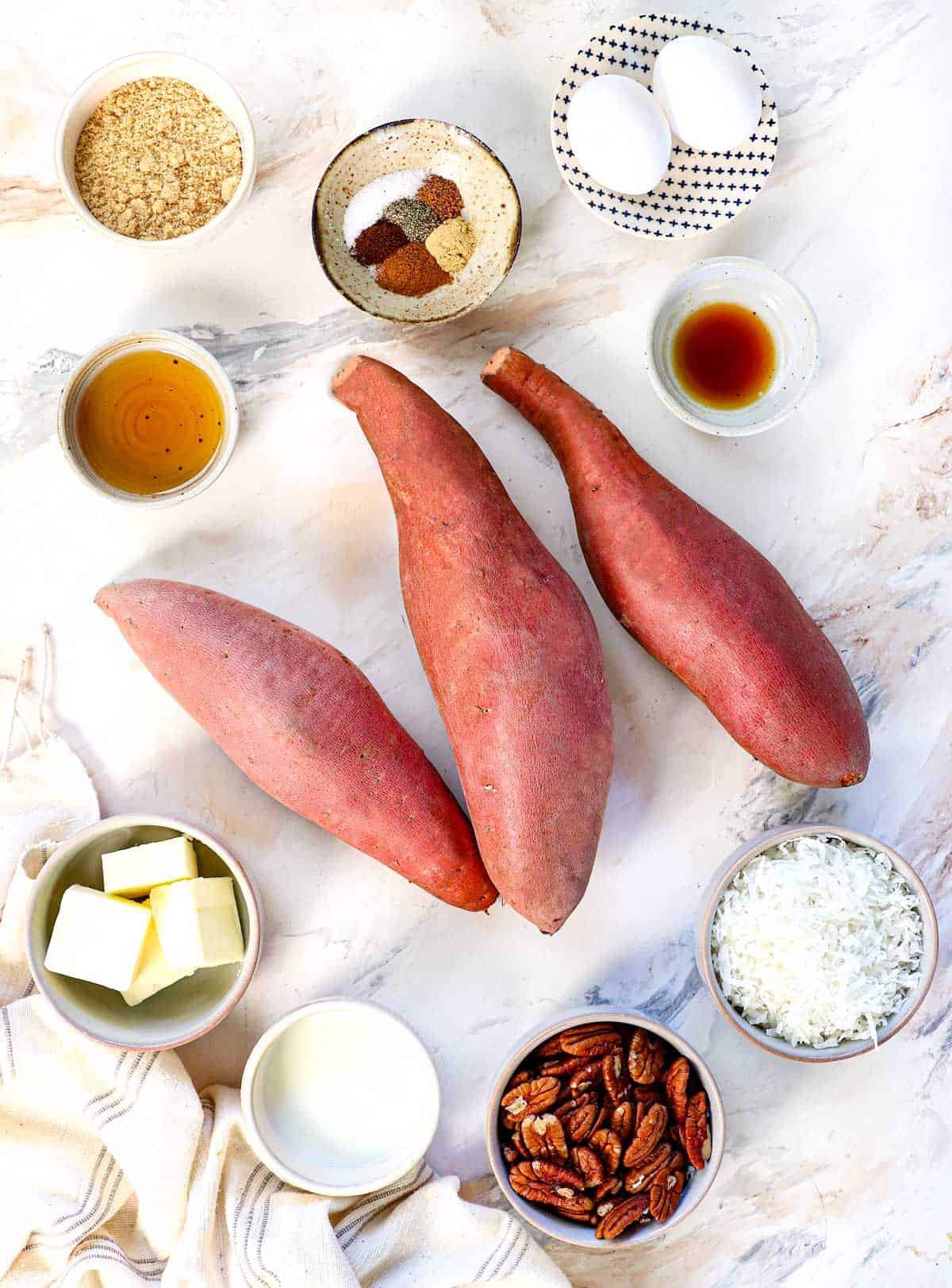 Top view of Sweet Potato Casserole Ingredients: sweet potatoes, butter, brown sugar, maple, milk, vanilla extract, coconut, pecans