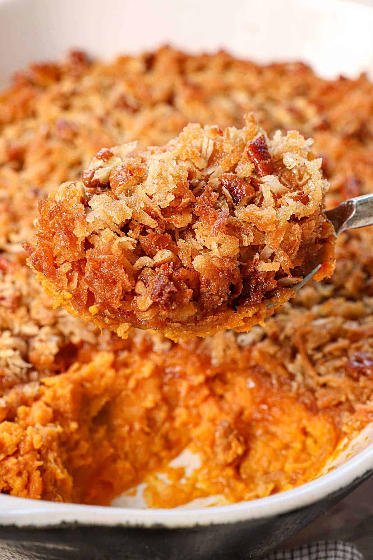 scooping up recipe for sweet potato casserole showing the creamy potatoes and crunchy pecan topping