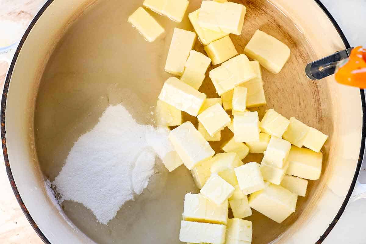 showing how to make almond roca by adding toffee ingredients to a stockpot: butter, sugar, corn syrup, water