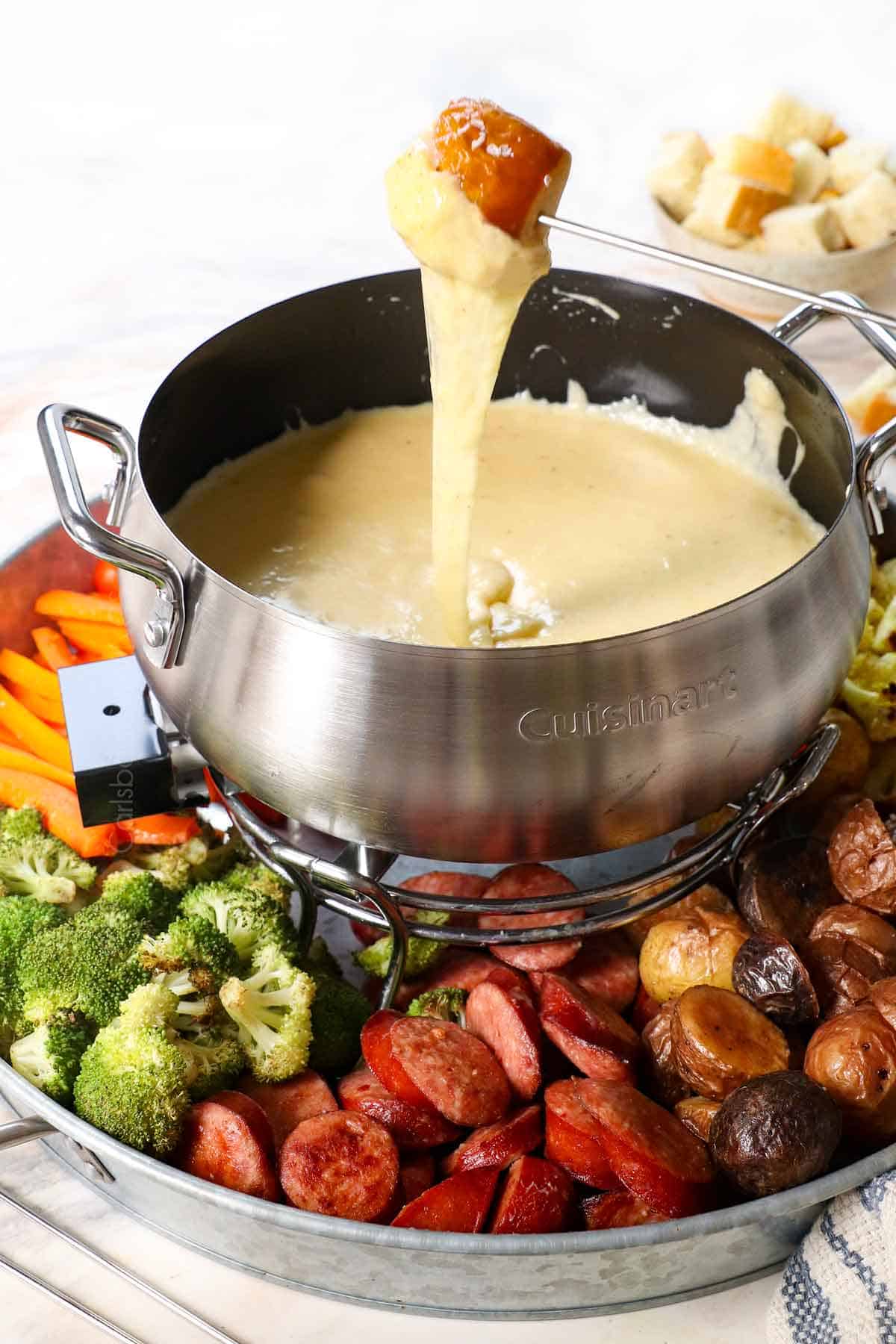 pulling bread from the fondue recipe showing how silky smooth the cheese is