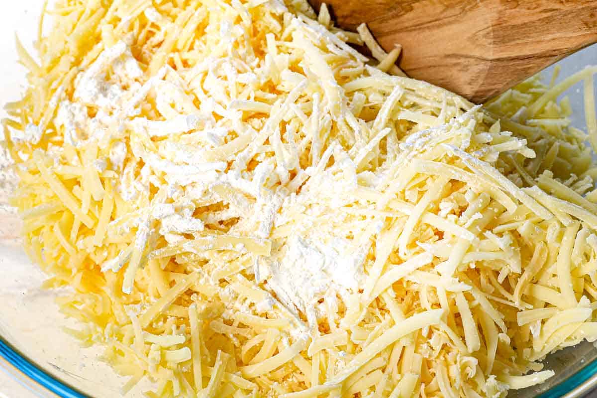 showing how to make fondue by tossing the shredded cheeses with cornstarch