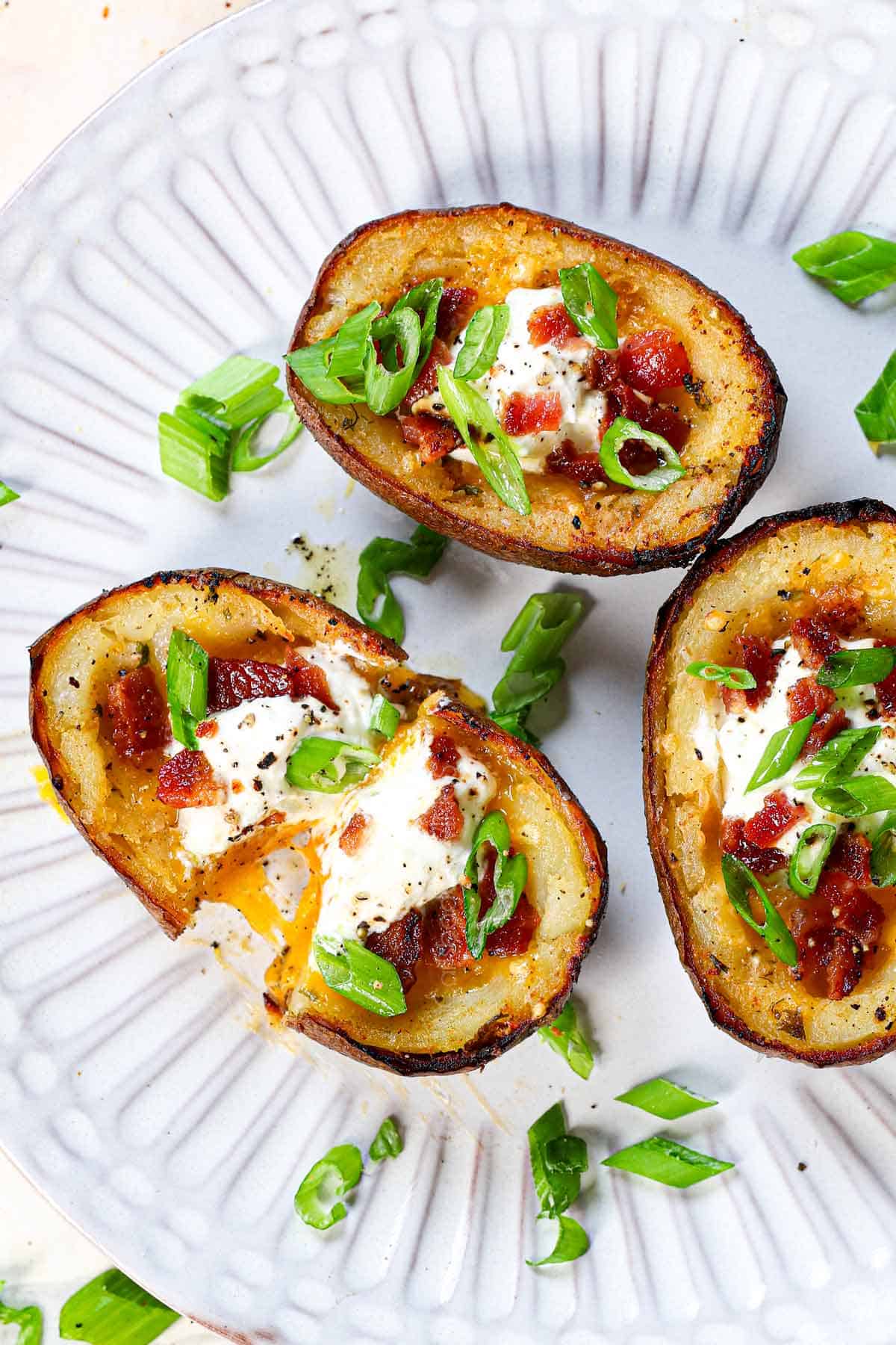 showing how cheesy the potato skins are by pulling one apart on a plate