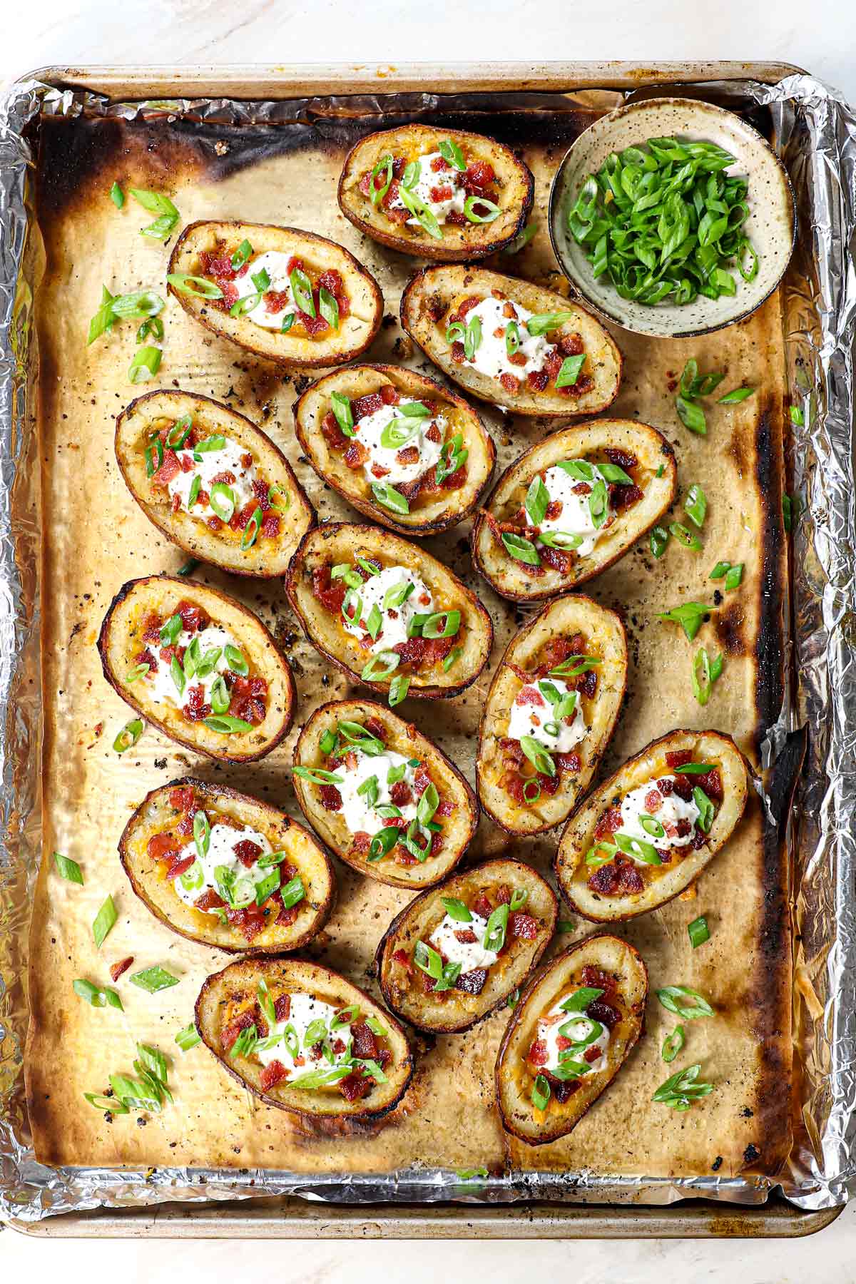 top view of potato skins recipe on a baking sheet being served with green onions