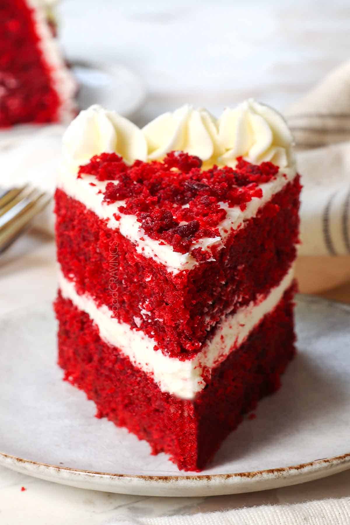 a slice of the best red velvet cake recipe with cream cheese frosting