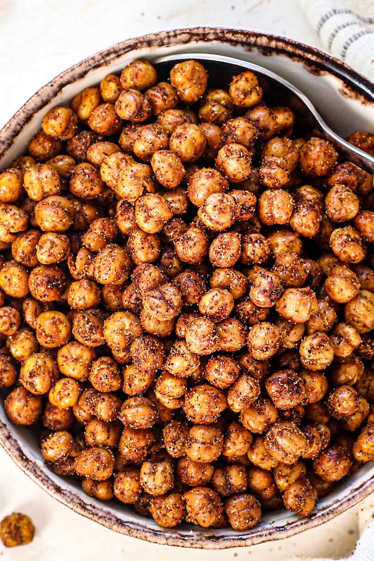 up close of roasted chickpeas recipe on a baking sheet being scooped by a spoon showing the spices
