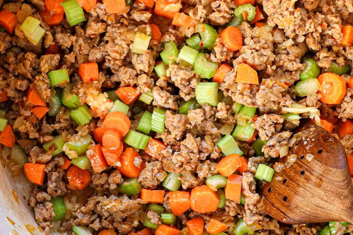 showing how to make white bean soup by cooking the carrots, celery and garlic with the sausage