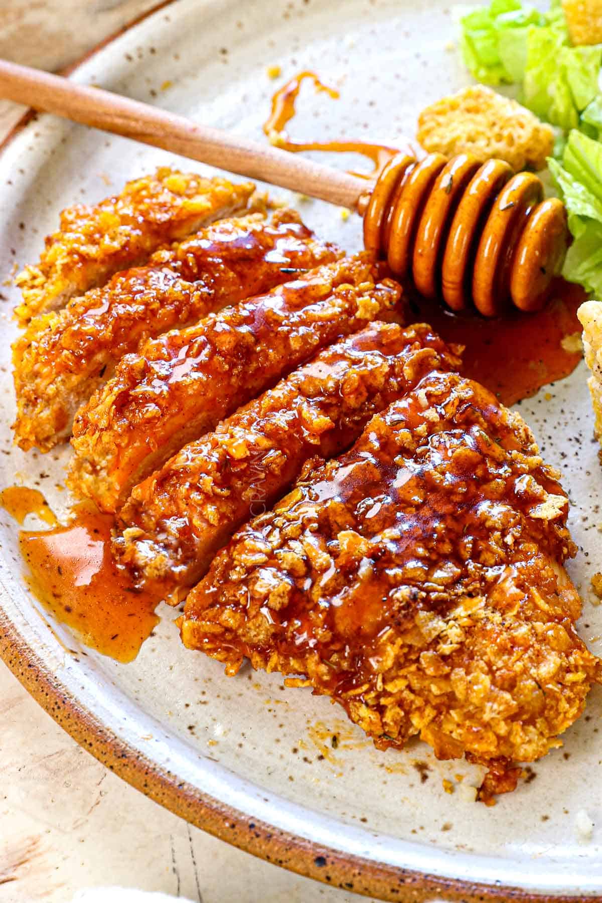 serving hot honey chicken on a plate with cornbread and salad