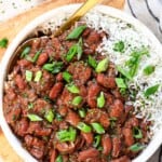top view of red beans and rice being served in a bowl garnished with parsley and green onions
