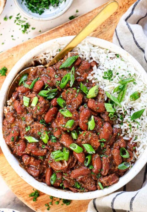 top view of red beans and rice being served in a bowl garnished with parsley and green onions