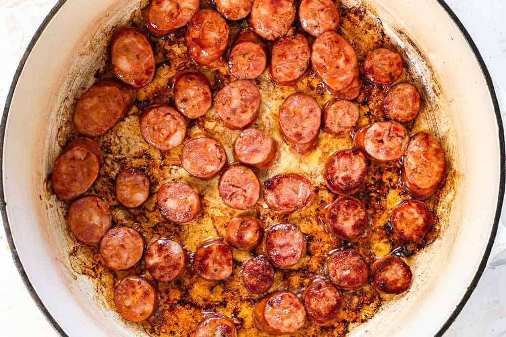 showing how to make red beans and rice by browning the sausage in a Dutch oven