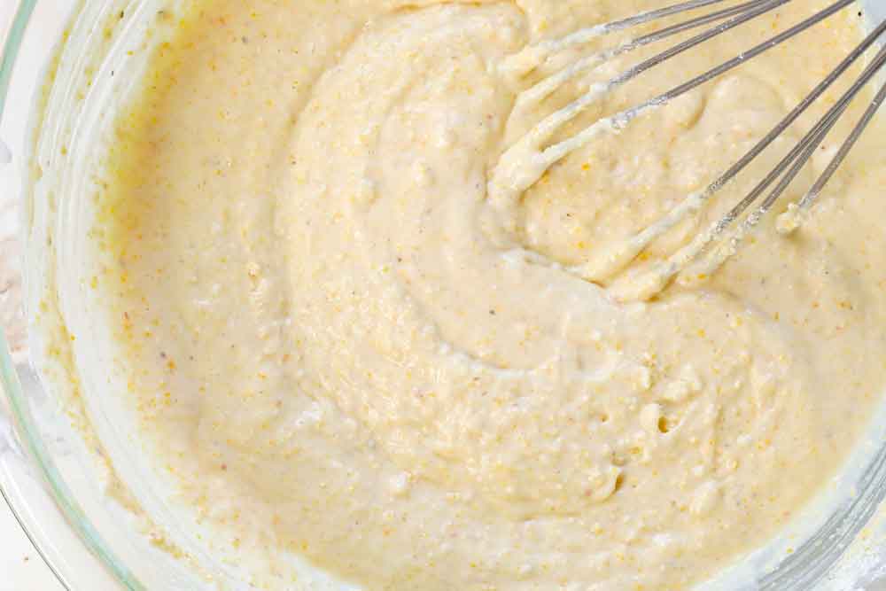 showing how to make skillet cornbread recipe by whisking the wet and dry ingredients together
