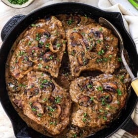 showing how to make smothered pork chops by resting in the sauce