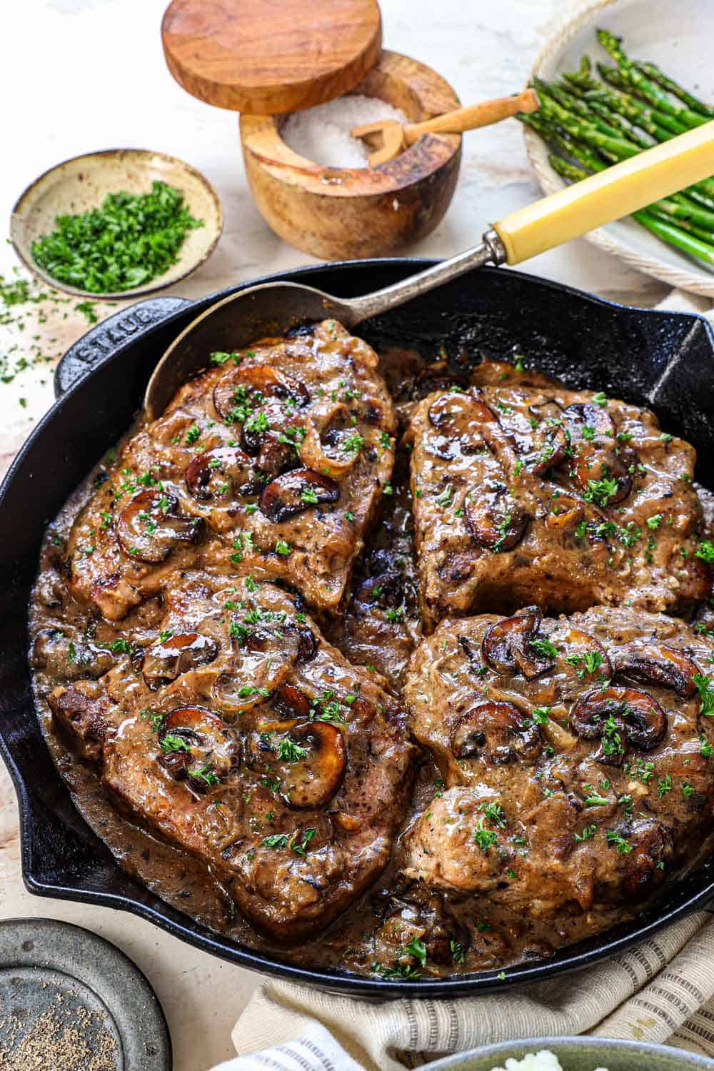 smothered pork chop recipe in a skillet showing the consistency of the gravy