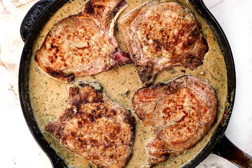 showing how to make smothered pork chops by adding the pork to the gravy and simmering