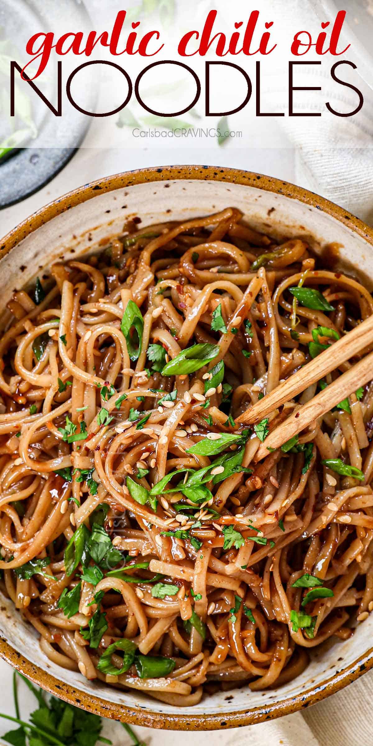 top view of spicy noodles with chili oil in a bowl being eaten with chopsticks