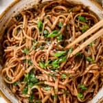 top view of spicy noodles with chili oil in a bowl being eaten with chopsticks