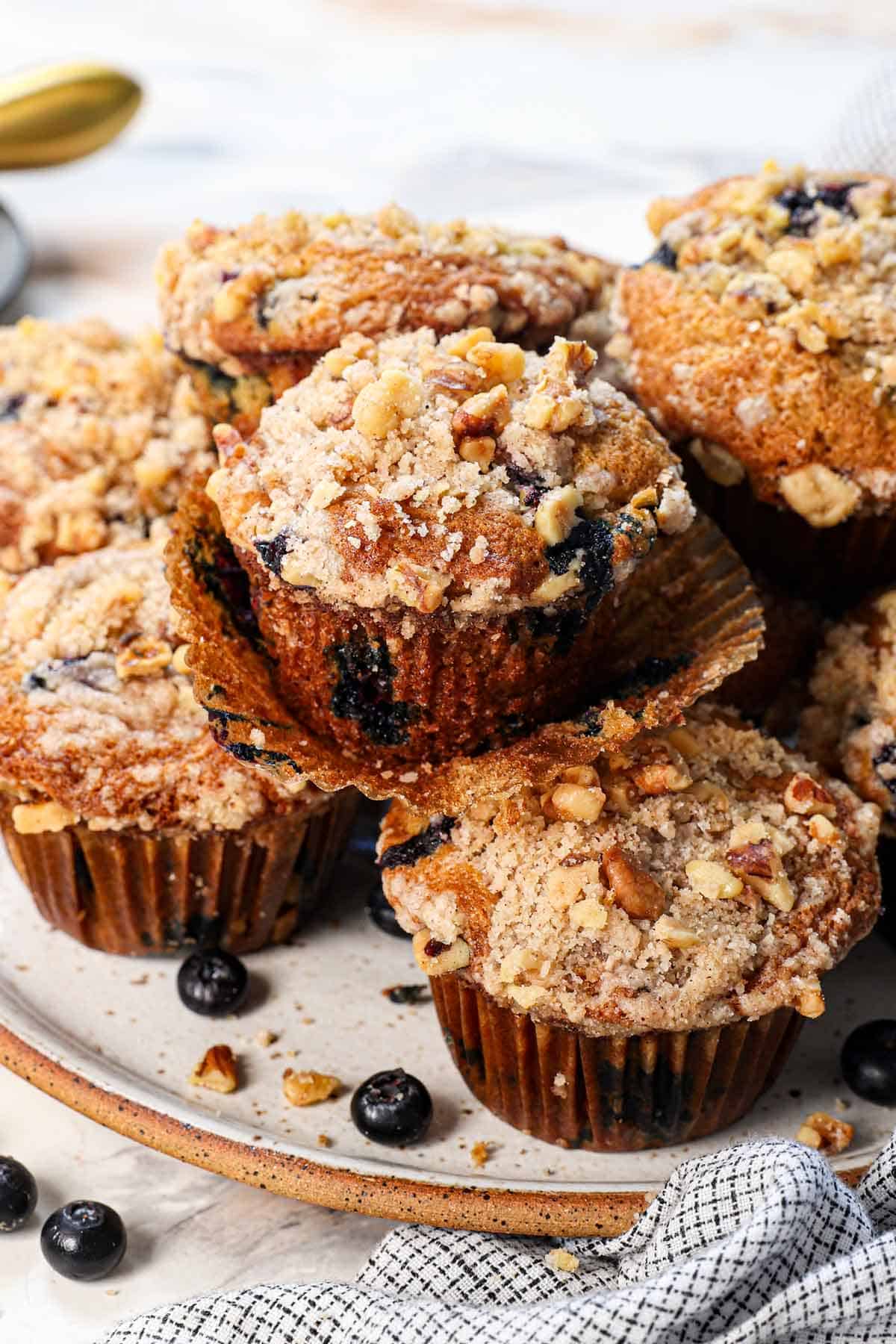 showing how to serve blueberry muffins with streusel topping stacked on a plate