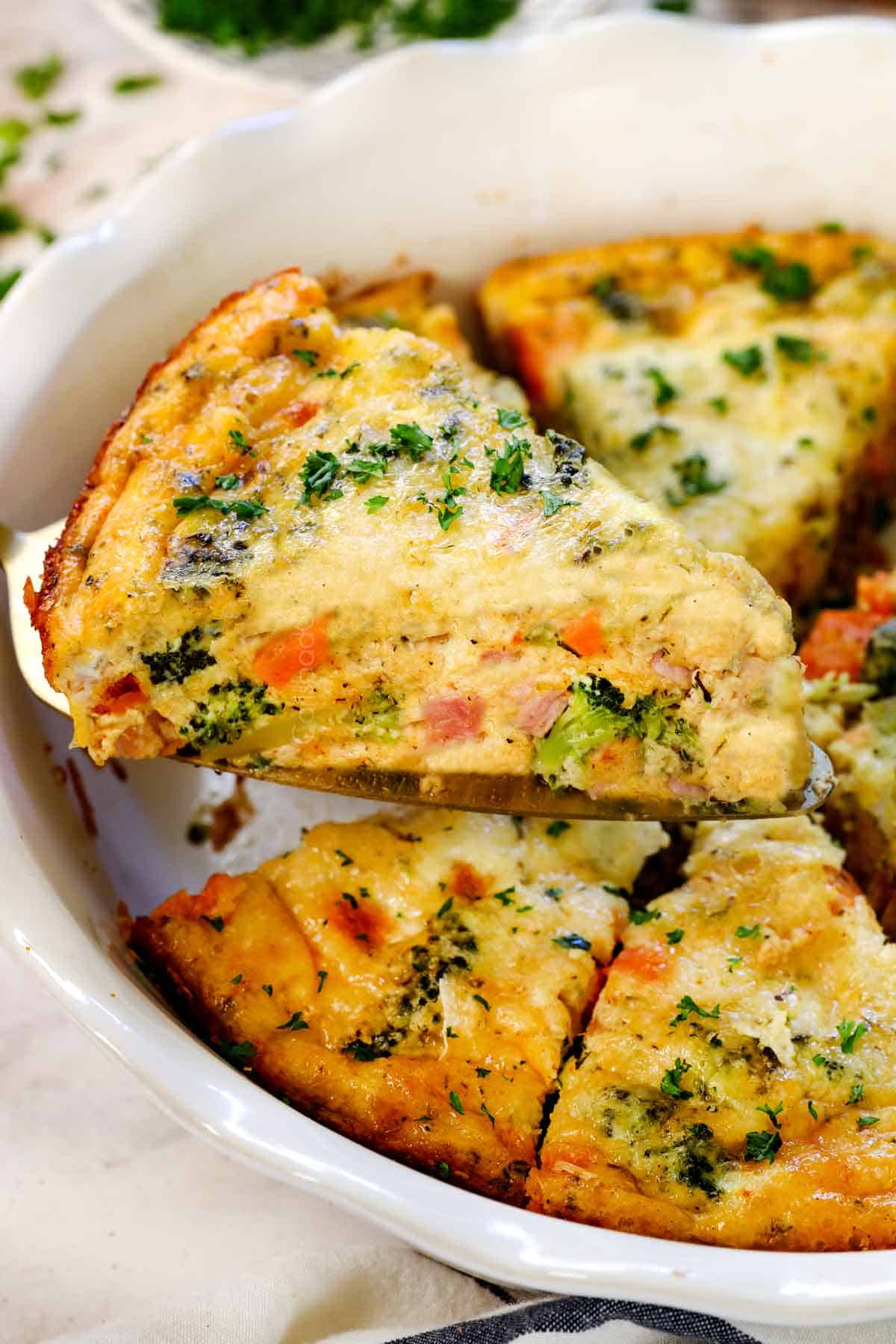 holding up a slice of crustless broccoli quiche showing how it holds its shape