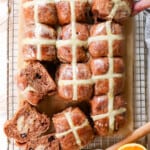 top view of hot cross buns with two hands pulling the rolls apart showing the crosses on the top