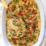 top view of holding mashed potato casserole recipe showing the panko topping, cheeses, bacon and, green onions