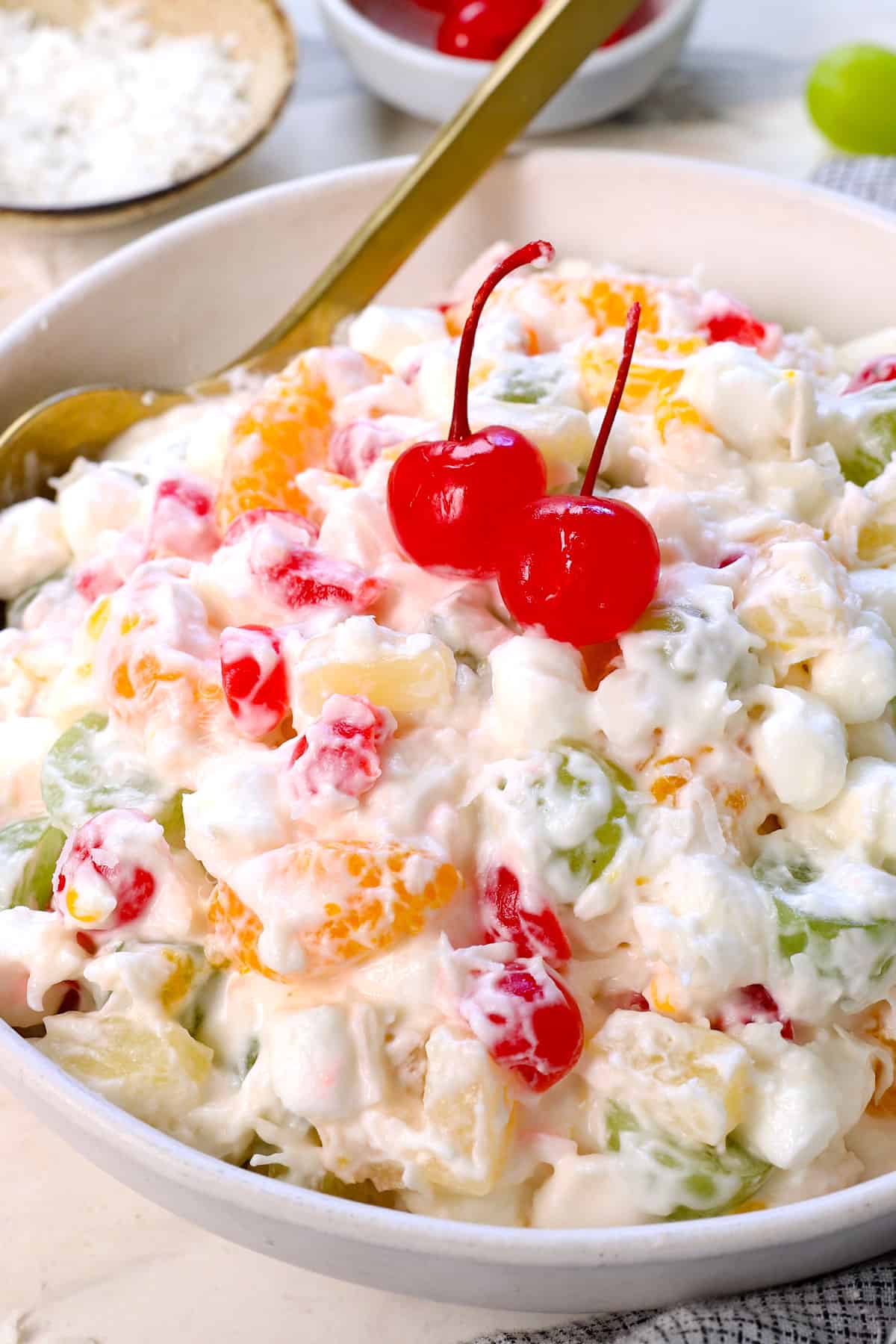 ambrosia fruit salad recipe in a bowl topped with cherries