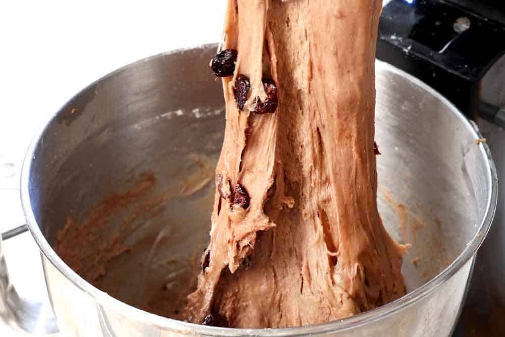 showing how to make hot cross buns by stretching the dough to show the perfect consistency