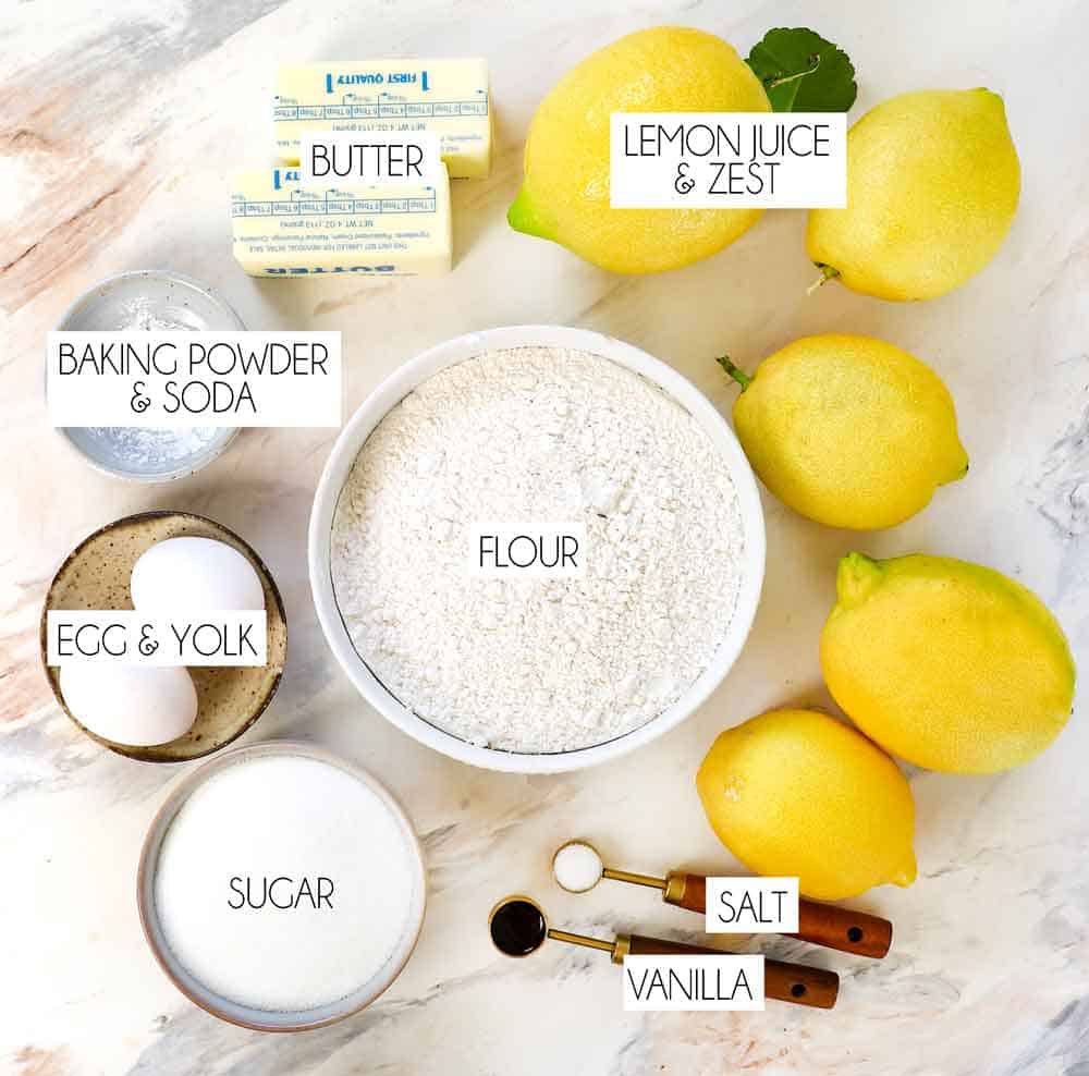 top view of lemon cookie recipe ingredients: lemon juice, lemon zest, flour, butter, egg, sugar, vanilla, salt, powdered sugar, cream cheese