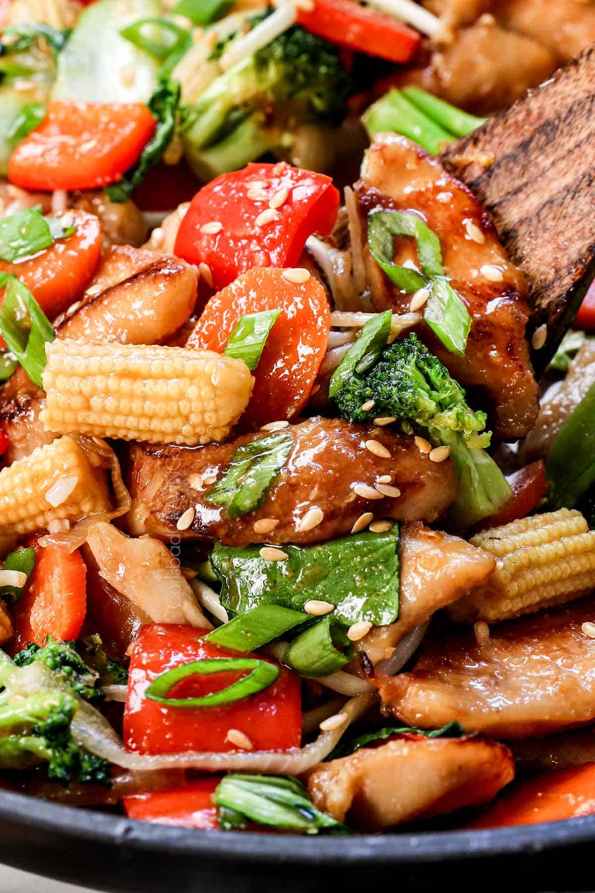 showing how to make chop suey by garnishing with sesame seeds and green onions