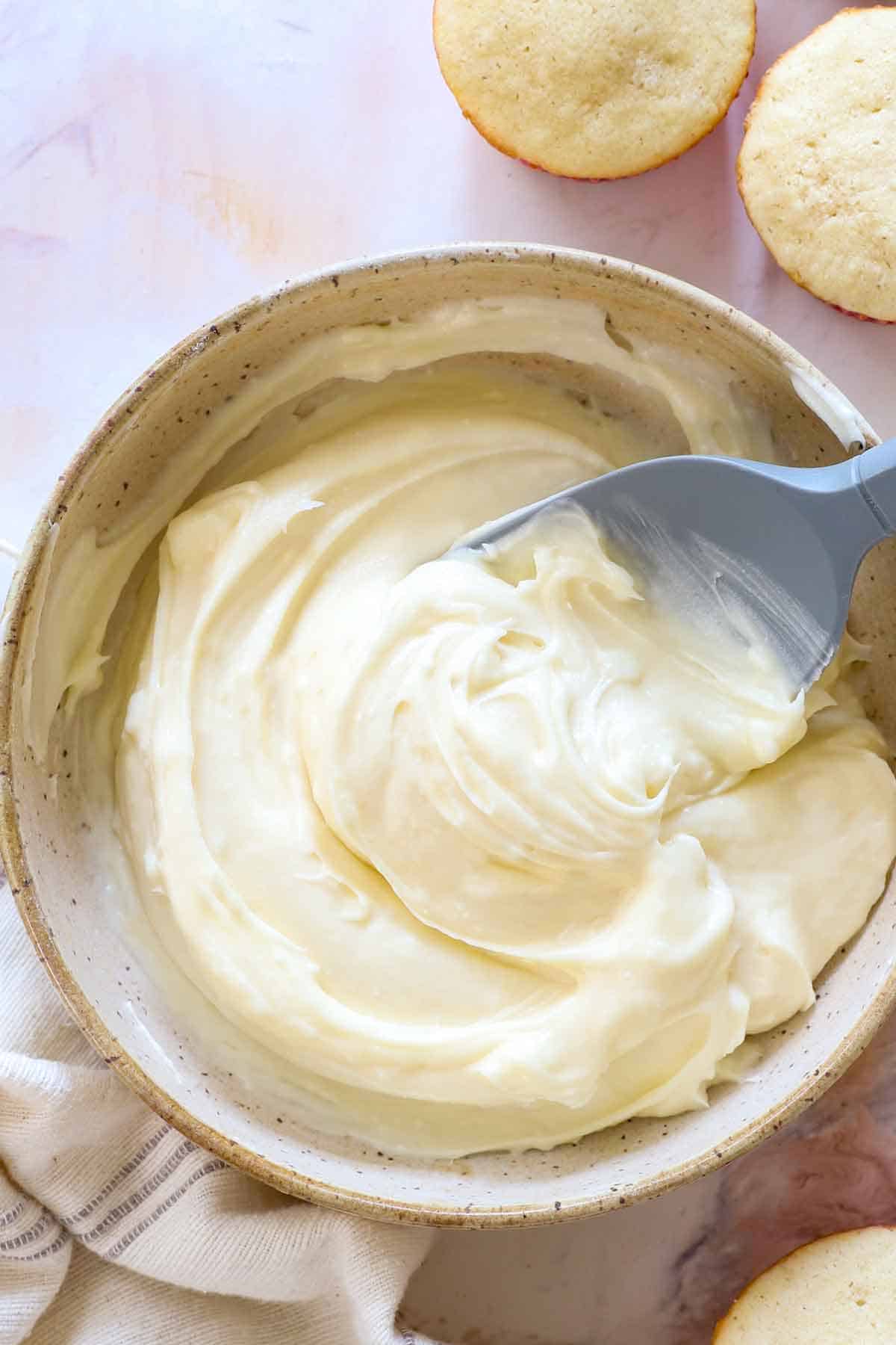 a bowl of cream cheese frosting in a recipe showing how thick, fluffy and creamy it is