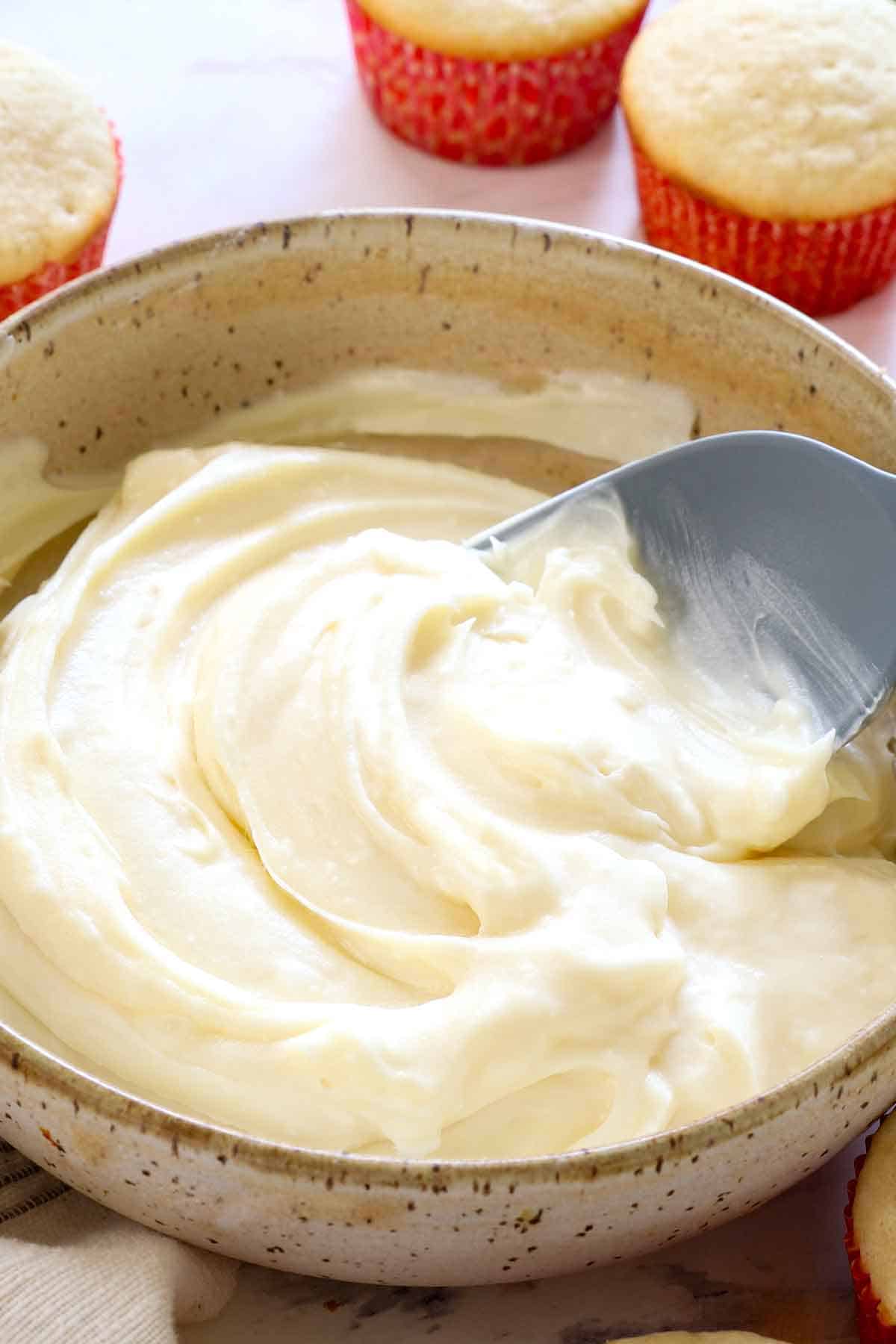 best homemade cream cheese frosting recipe ina bowl with a spoon showing how thick and fluffy it is