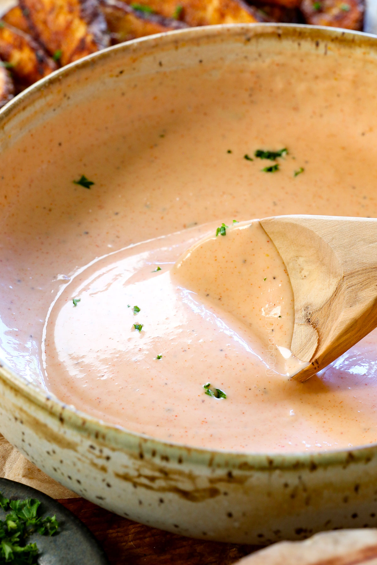 a spoon scooping up fry sauce for dipping showing the color and creaminess