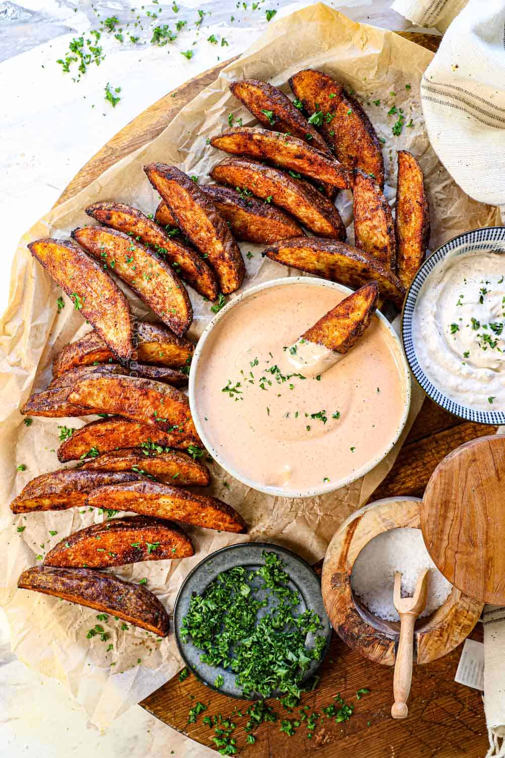 top view of baked potato wedges in the oven being served with fry sauce and garlic aioli on a platter